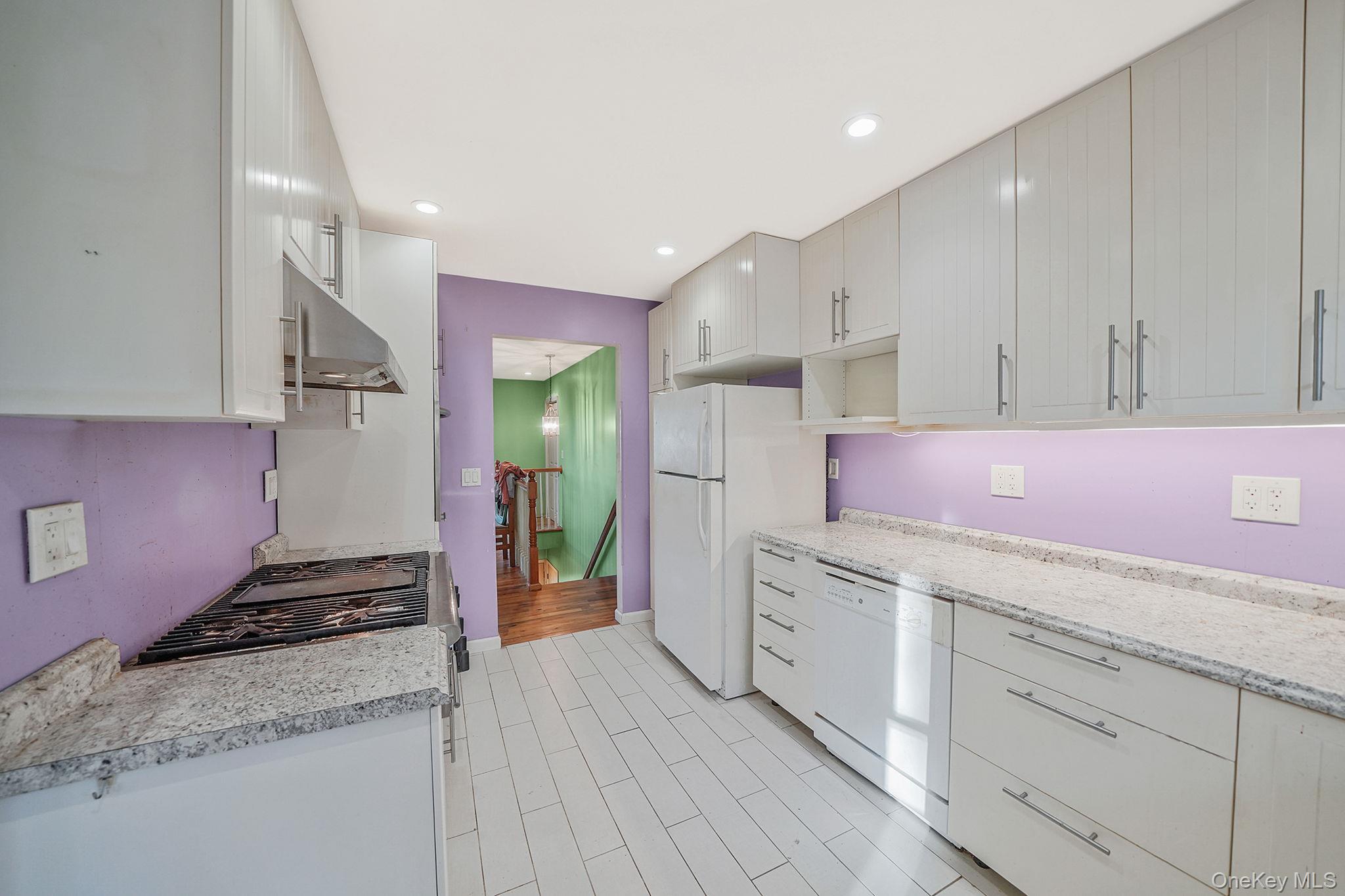97 Locust Drive Rocky Point, NY 11778 - Photo 12 of 26 Kitchen with light countertops, recessed lighting, white cabinets, under cabinet range hood, and white appliances