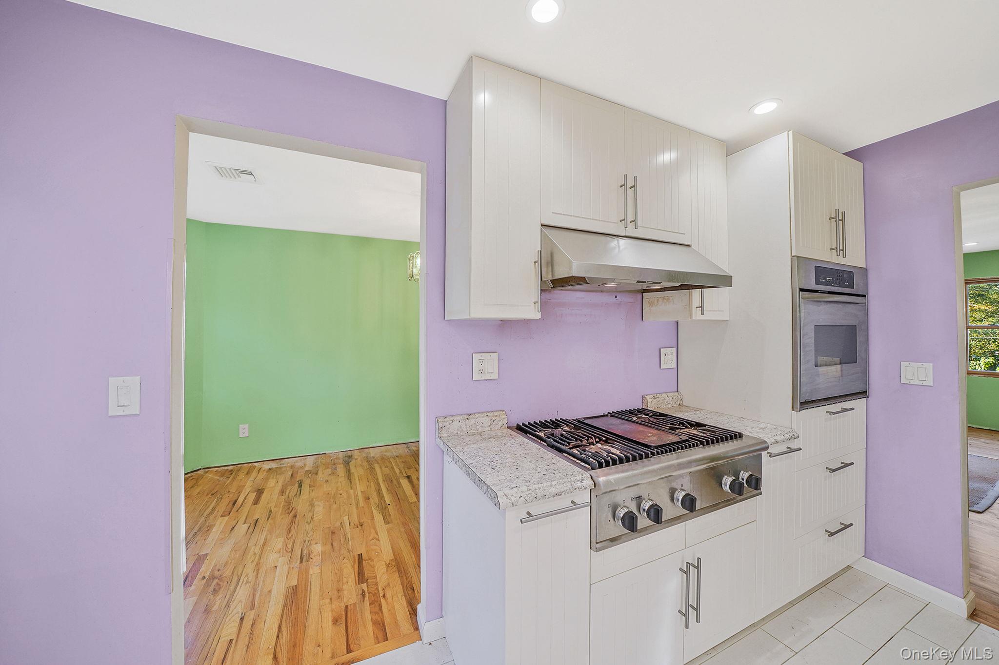 97 Locust Drive Rocky Point, NY 11778 - Photo 13 of 26 Kitchen featuring stainless steel appliances, light countertops, under cabinet range hood, white cabinets, and light wood-style flooring