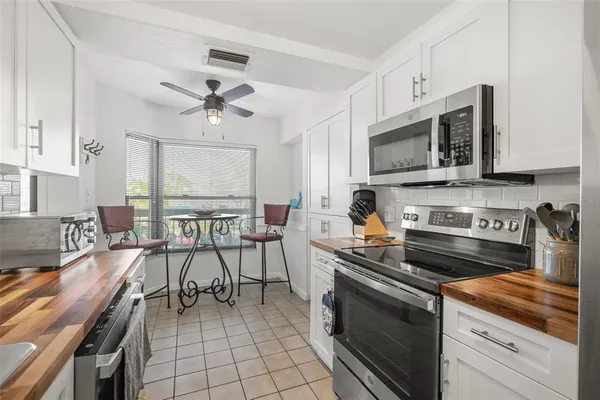 a kitchen with stainless steel appliances granite countertop a stove white cabinets a sink dishwasher and a stove with wooden floor