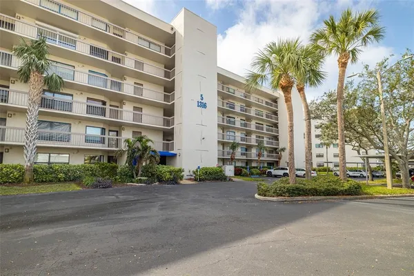 a front view of a multi story residential apartment building with yard and traffic signal