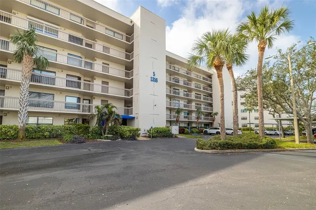 a front view of a multi story residential apartment building with yard and traffic signal