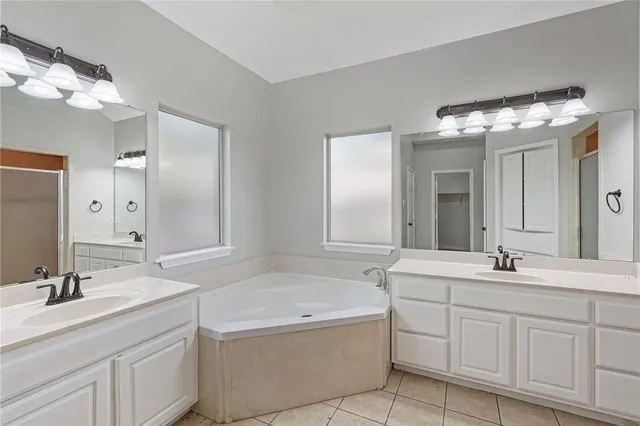 a bathroom with a double vanity sink mirror and bathtub