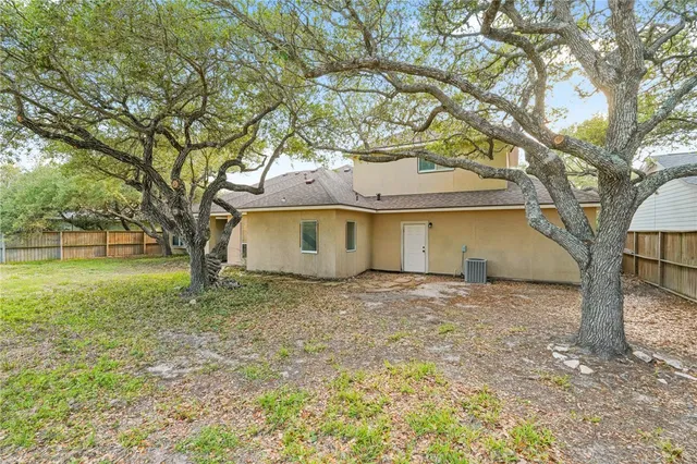 a view of a house with a yard and large tree