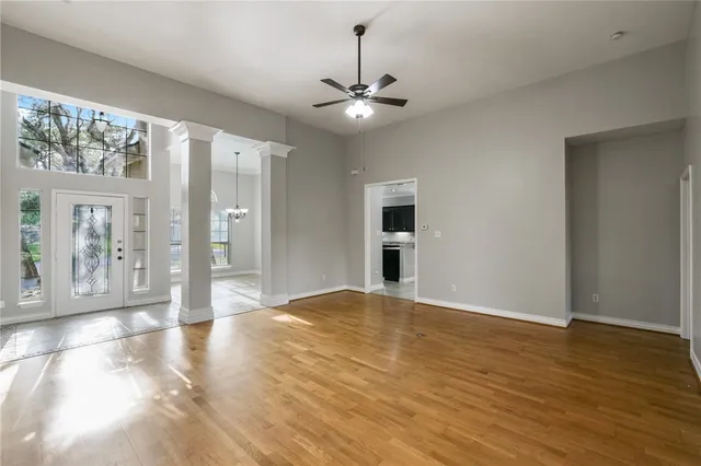 a view of an empty room with window and wooden floor