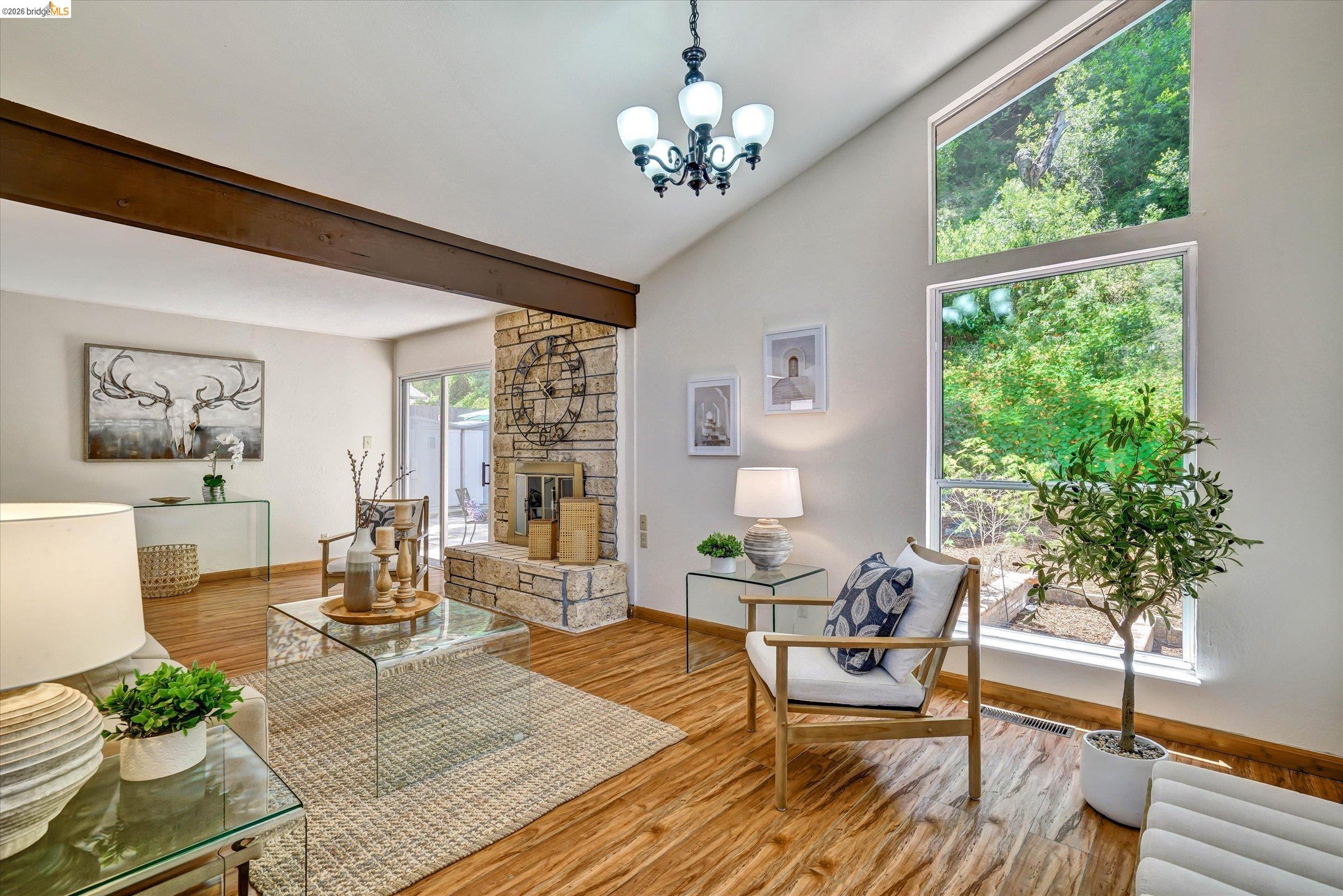 2826 Wright Avenue Pinole, CA 94564 - Photo 10 of 70 Living area featuring vaulted ceilings with exposed beam, stone-clad fireplace, wood-finish flooring, and large windows with abundant natural light