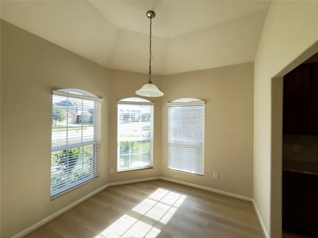 a view of an empty room with window and chandelier fan