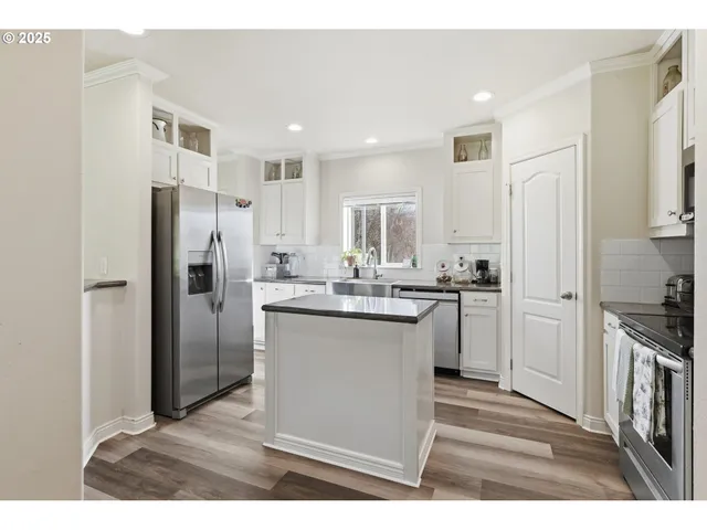 a kitchen with stainless steel appliances kitchen island granite countertop a refrigerator a stove and a sink