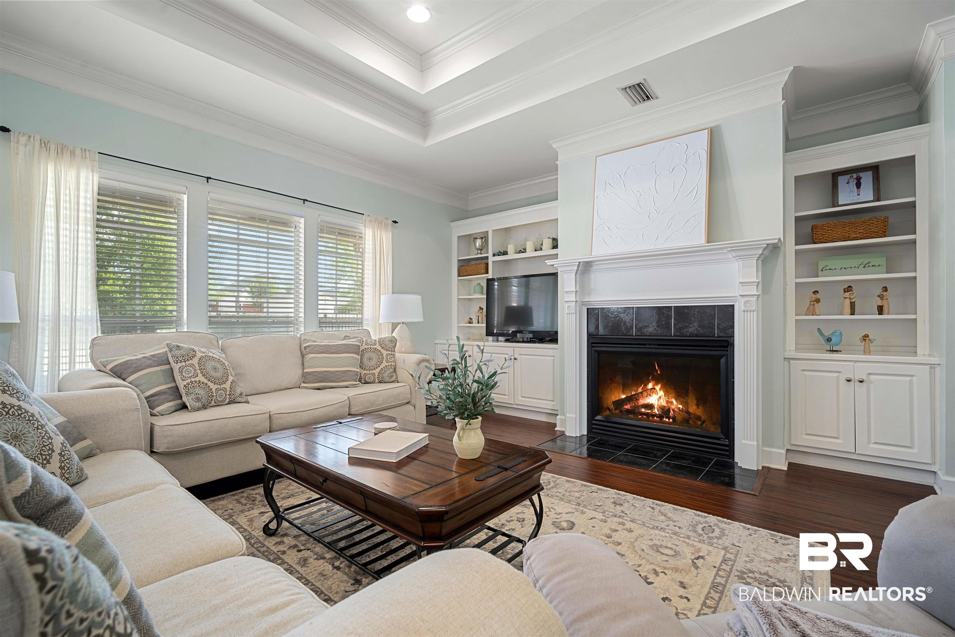 9552 White Castle Road Mobile, AL 36695 - Photo 5 of 31 Living room with a tiled fireplace, crown molding, dark wood-type flooring, and a raised ceiling