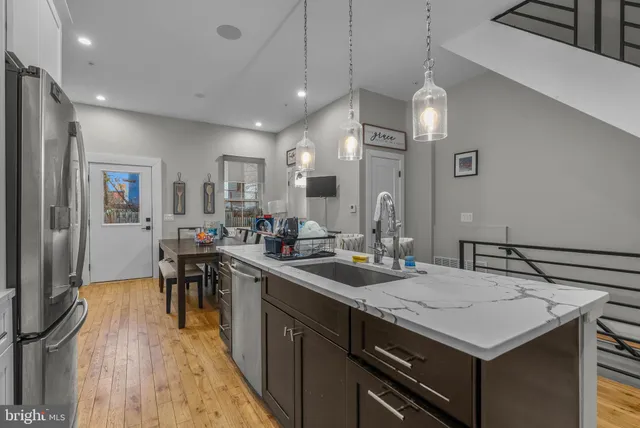 a kitchen with a stove a sink a kitchen island with chairs and wooden floor