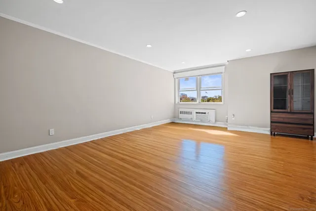 a view of empty room with wooden floor and window