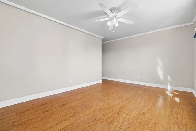 an empty room with wooden floor and fan