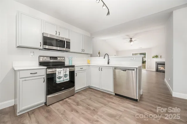 a kitchen with stainless steel appliances white cabinets a sink a stove a microwave and cabinetry