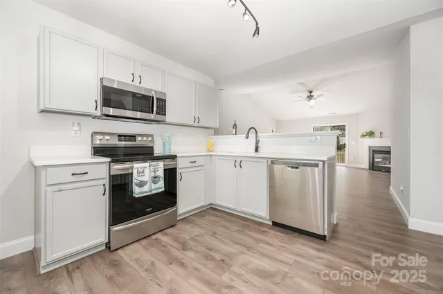 a kitchen with stainless steel appliances white cabinets a sink a stove a microwave and cabinetry