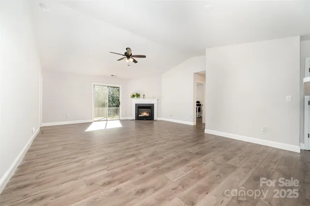 a view of an empty room with window and wooden floor