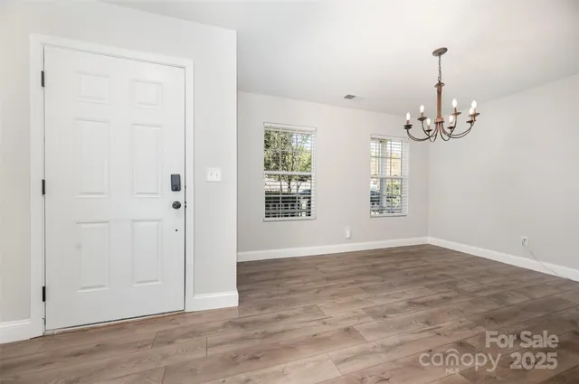 an empty room with wooden floor windows and entrance