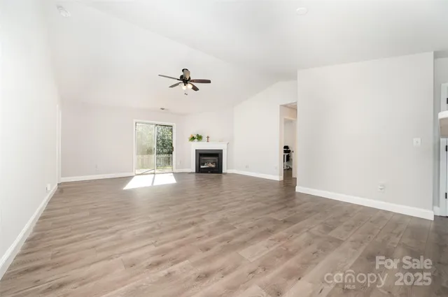 a view of an empty room with window and wooden floor