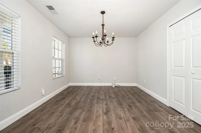 an empty room with wooden floor windows and entrance