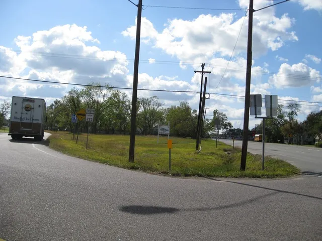 a view of a road with a big yard and palm tree