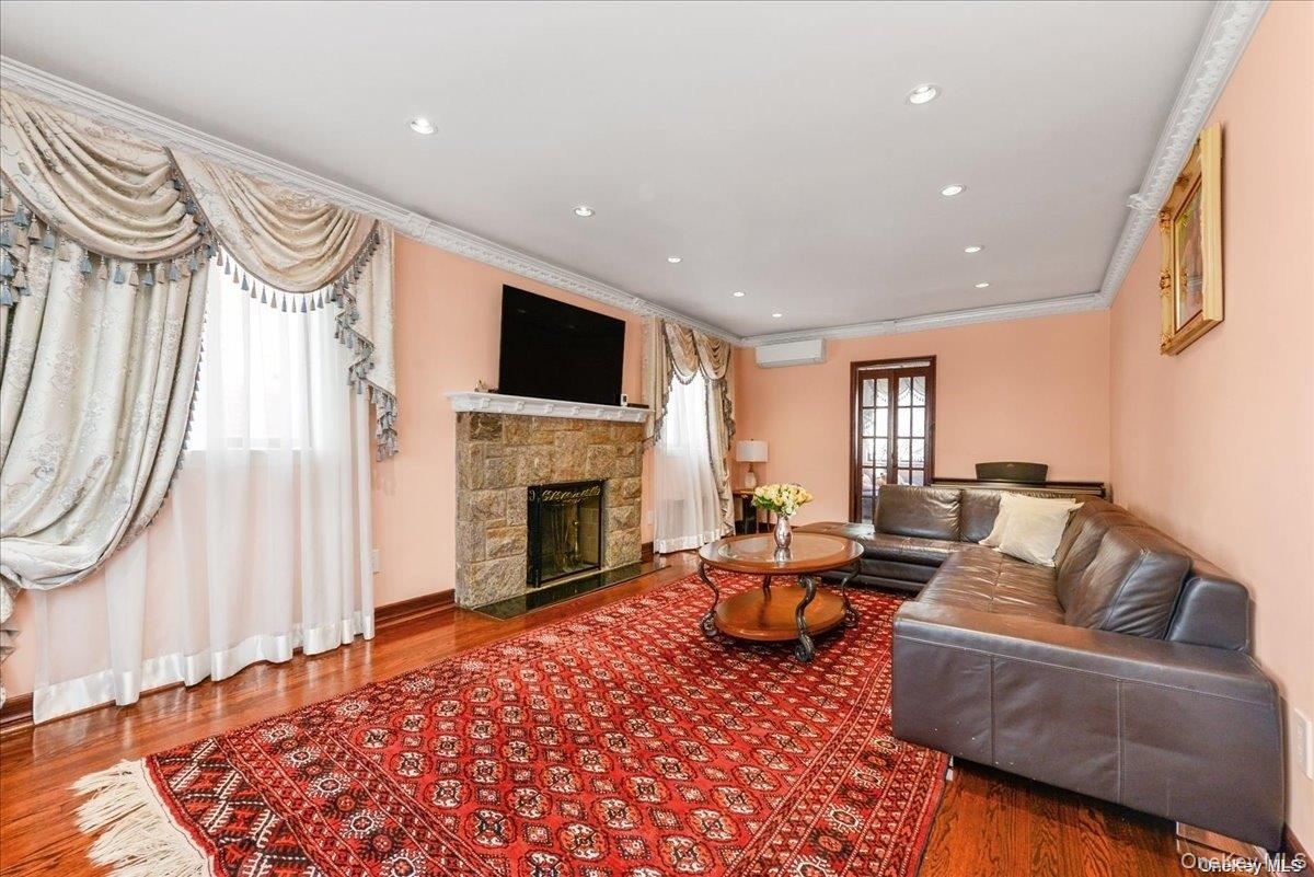 87-67 Chevy Chase Street Queens, NY 11432 - Photo 2 of 22 a living room with furniture a fireplace and a flat screen tv