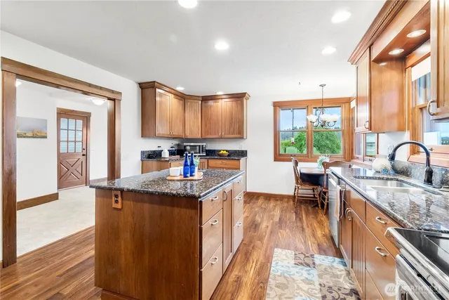 a kitchen with stainless steel appliances granite countertop a stove a sink and a wooden cabinets