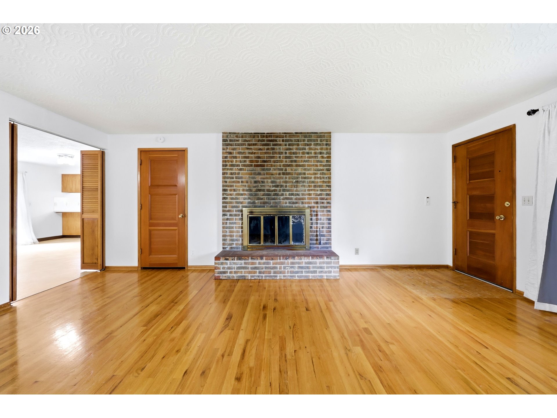 3003 Southeast 162nd Avenue Portland, OR 97236 - Photo 7 of 41 a view of an empty room with wooden floor and a fireplace