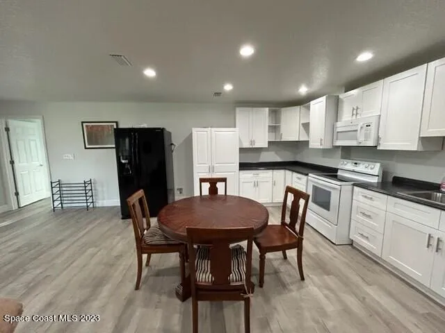 a kitchen with stainless steel appliances kitchen island granite countertop a dining table chairs and a refrigerator