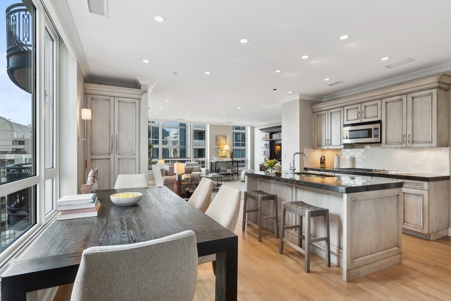 10 East Delaware Place, Unit 21D Chicago, IL 60611 - Photo 12 of 33 a large kitchen with stainless steel appliances granite countertop a stove top oven a sink a dining table and chairs