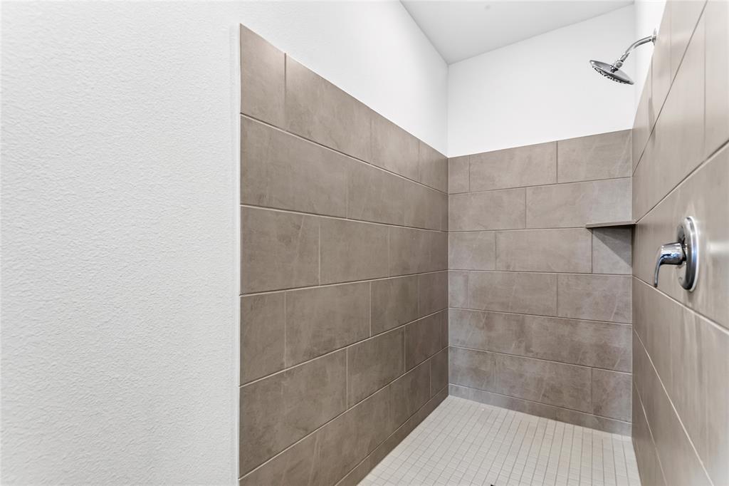656 Waymaker Way Princeton, TX 75407 - Photo 9 of 40 Walk-in shower with large-format grey wall tiles, a rainfall showerhead, and a chrome single-handle faucet
