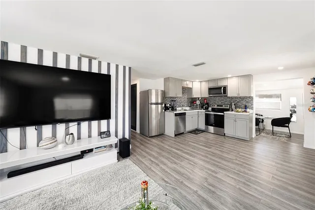 a living room with stainless steel appliances furniture and a kitchen view