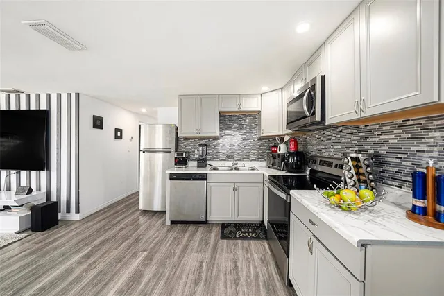 a kitchen with a sink dishwasher stove and white cabinets
