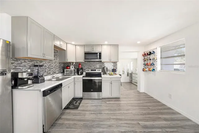 a kitchen with granite countertop a refrigerator stove top oven and sink