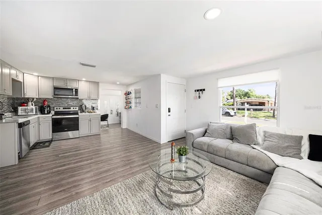 a living room with furniture kitchen and a wooden floor