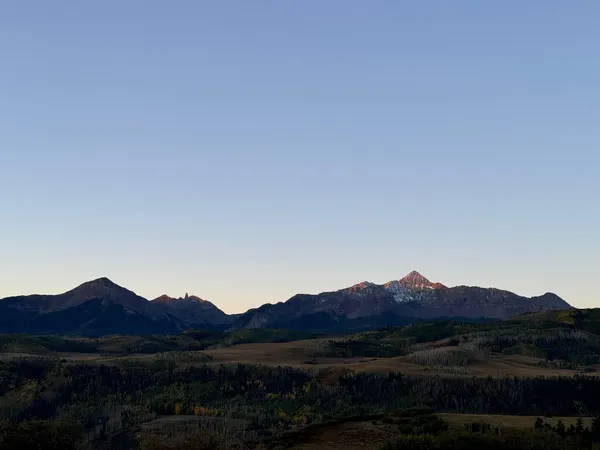 a view of a dry field with mountains in the background