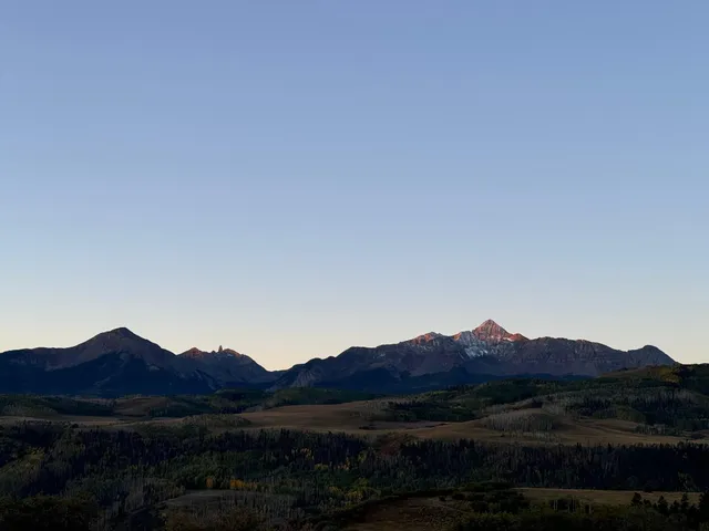 a view of a dry field with mountains in the background