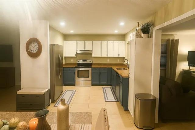 a kitchen with stainless steel appliances kitchen island granite countertop a refrigerator a stove and a sink