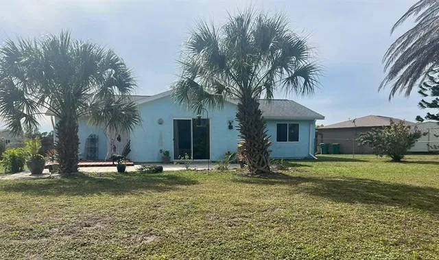 a white house with a big yard and palm trees