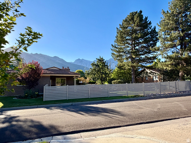 2924 Robidoux Road Sandy, UT 84093 - Photo 63 of 68 Mountain backdrop, mature trees, horizontal slat fencing, expansive paved street, manicured lawn