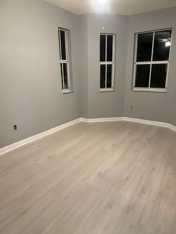 a view of an empty room with wooden floor and windows
