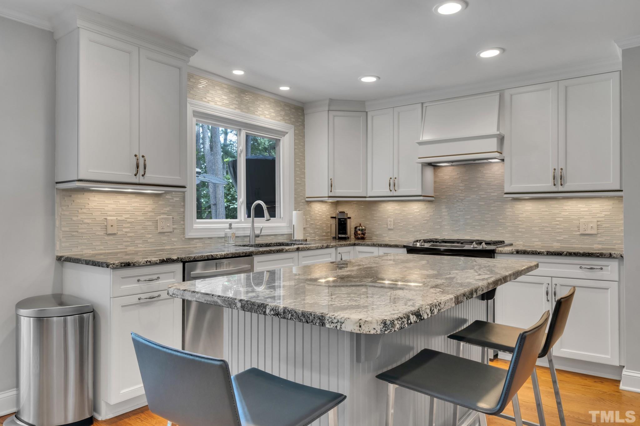 1617 Hunting Ridge Road Raleigh, NC 27615 - Photo 8 of 31 a kitchen with kitchen island granite countertop a sink chairs and cabinets