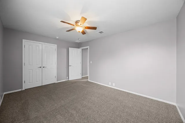 an empty room with a window and ceiling fan