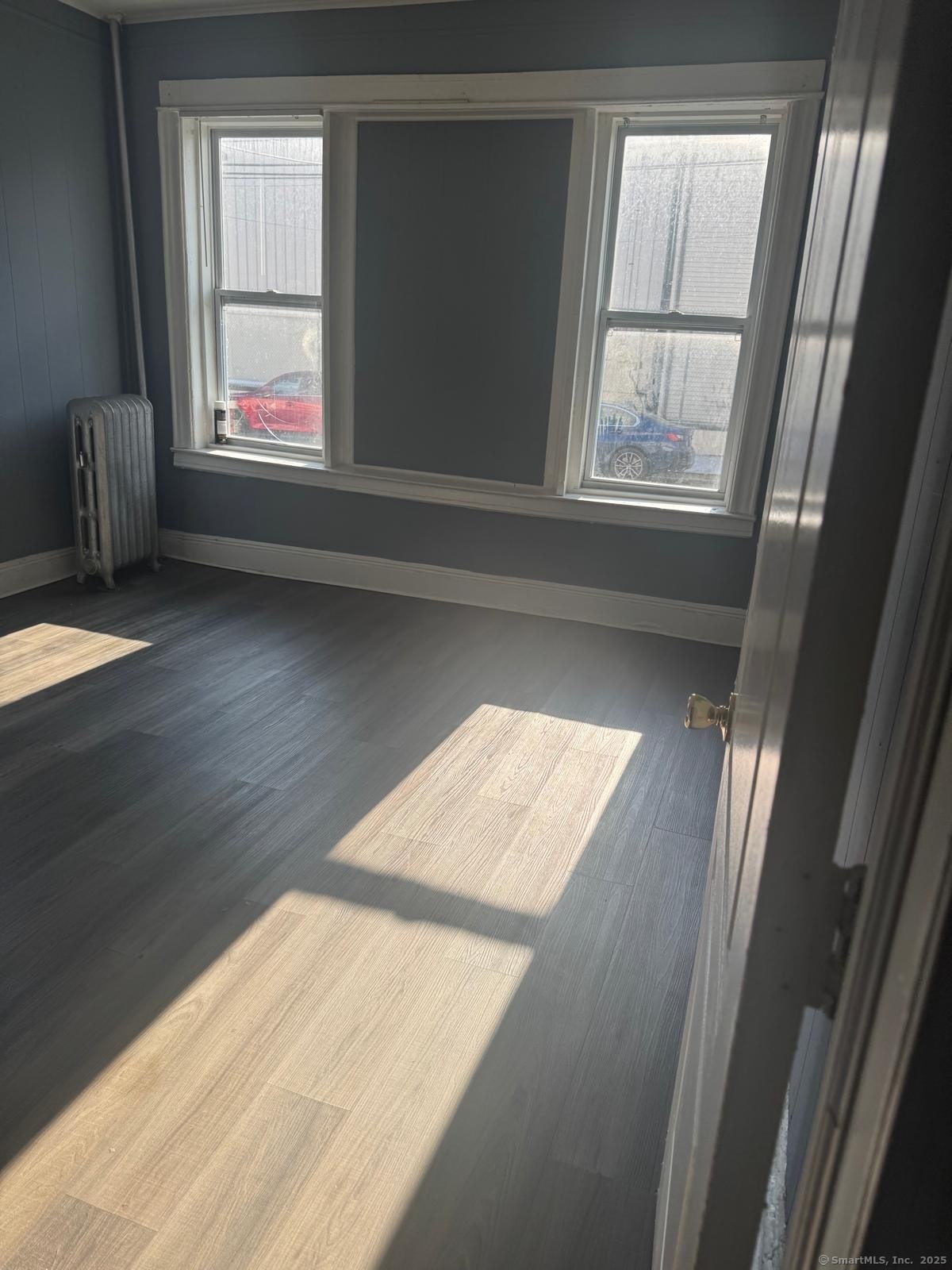 146 George Street, Unit 2 Bridgeport, CT 06604 - Photo 5 of 12 an empty room with wooden floor and windows