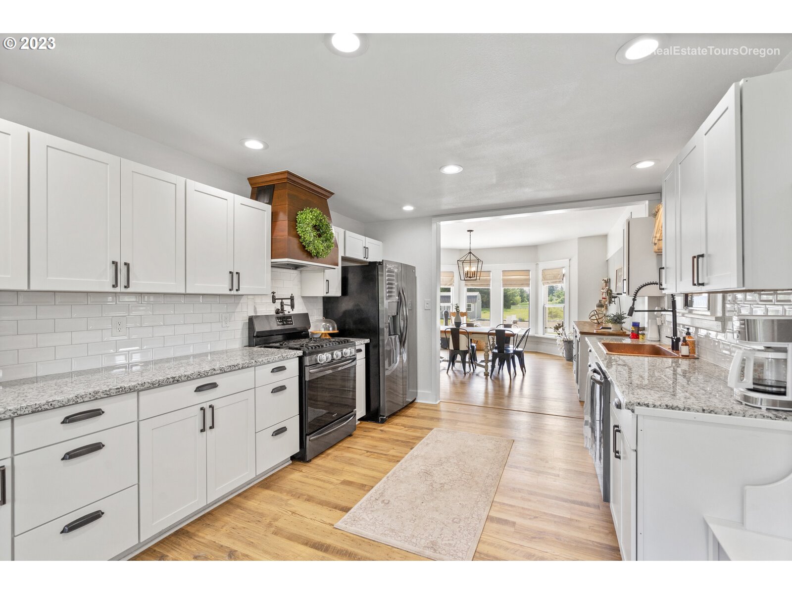 6970 South Knights Bridge Road Canby, OR 97013 - Photo 8 of 32 a kitchen with stainless steel appliances granite countertop a refrigerator a sink a stove and white cabinets with wooden floor