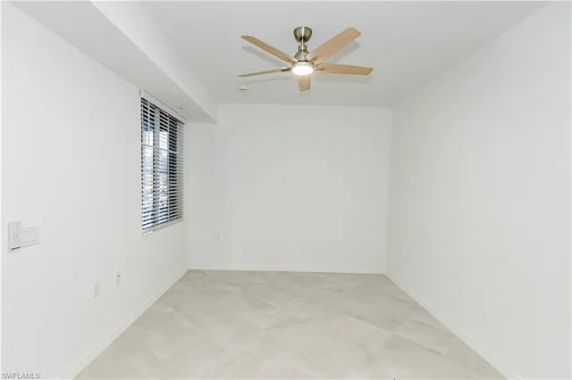 an empty room with a window and a ceiling fan