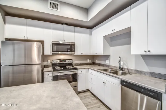 a kitchen with a sink a refrigerator and white cabinets
