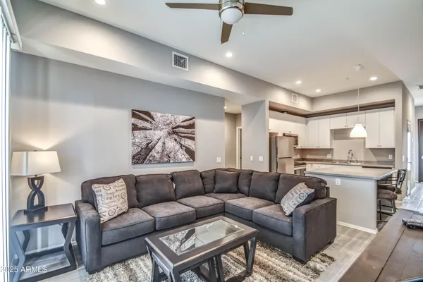 a living room with furniture kitchen view and a chandelier