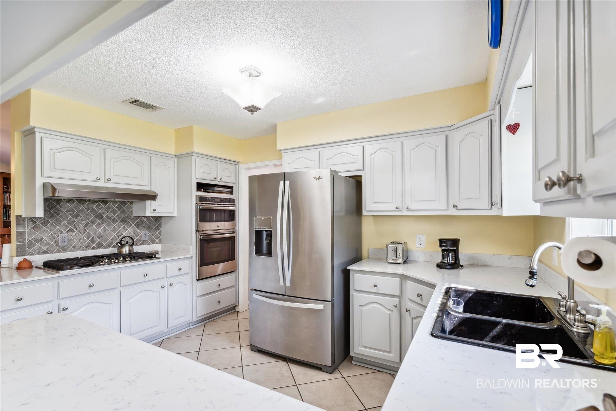 8710 Three Notch Road Mobile, AL 36619 - Photo 8 of 30 Kitchen featuring light tile patterned floors, appliances with stainless steel finishes, white cabinets, sink, and backsplash