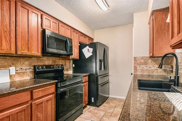 a kitchen with stainless steel appliances granite countertop a refrigerator stove and sink