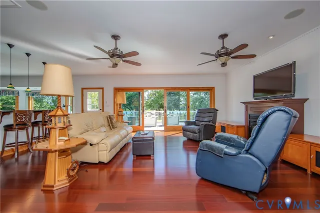 a living room with furniture a ceiling fan a flat screen tv and a large window