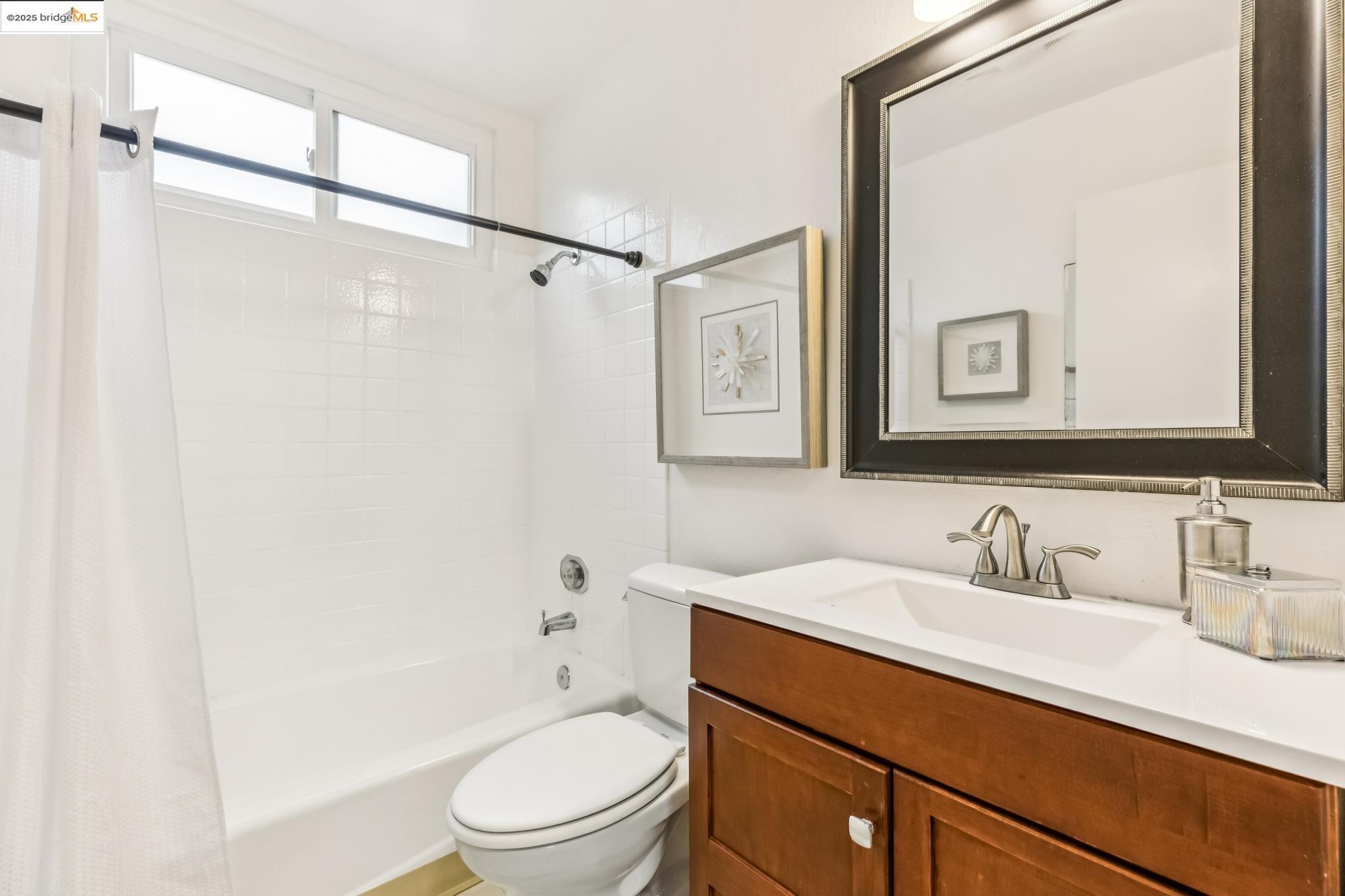5619 Doremus Avenue Richmond, CA 94805 - Photo 13 of 45 a bathroom with a sink a mirror a toilet and shower