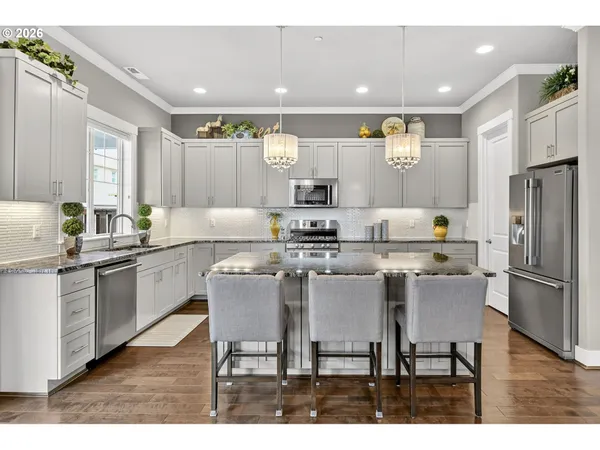 a kitchen with stainless steel appliances granite countertop a table chairs sink refrigerator and microwave